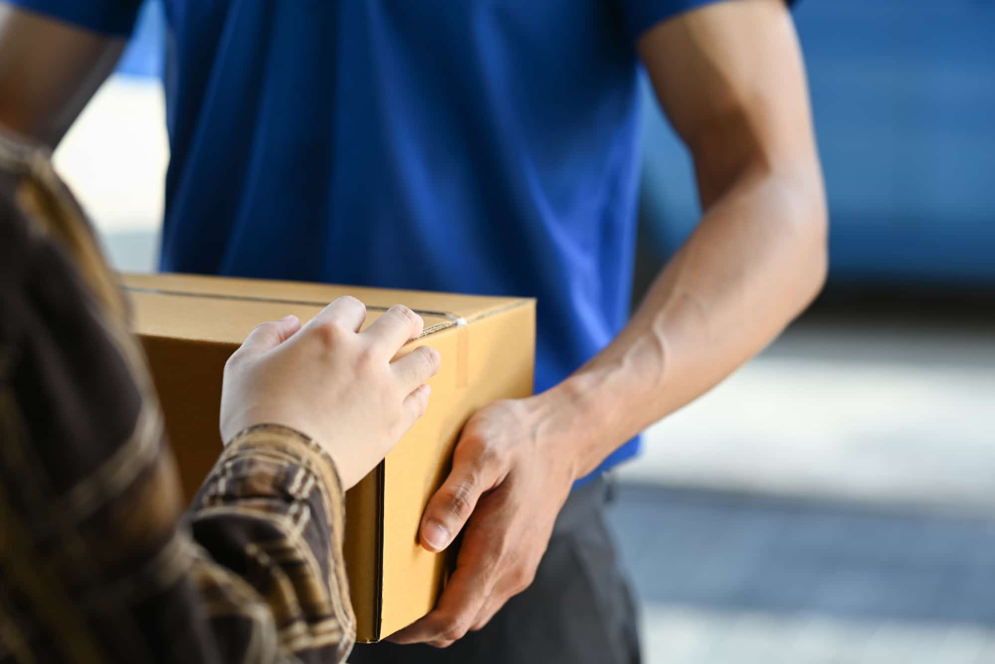 cropped view of delivery man giving carton box to girl